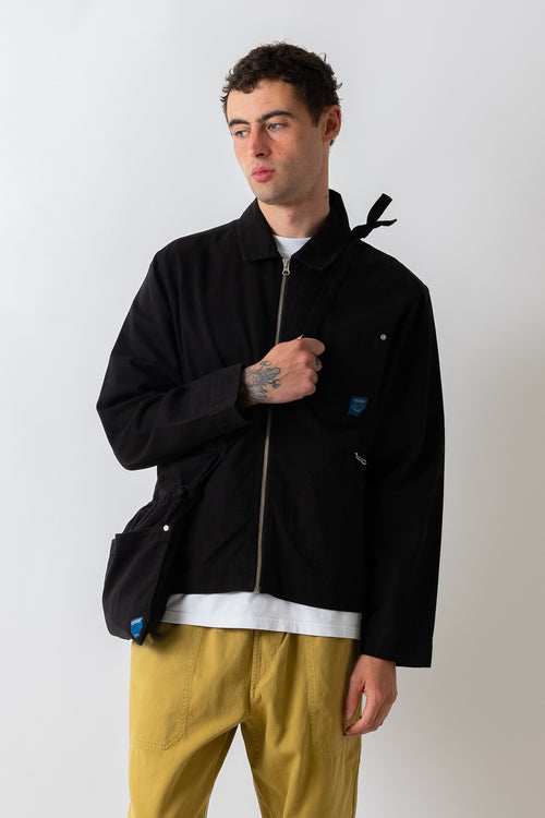 Closer front three-quarter view of a model carrying the Pexwear Apron Bag in Black.
