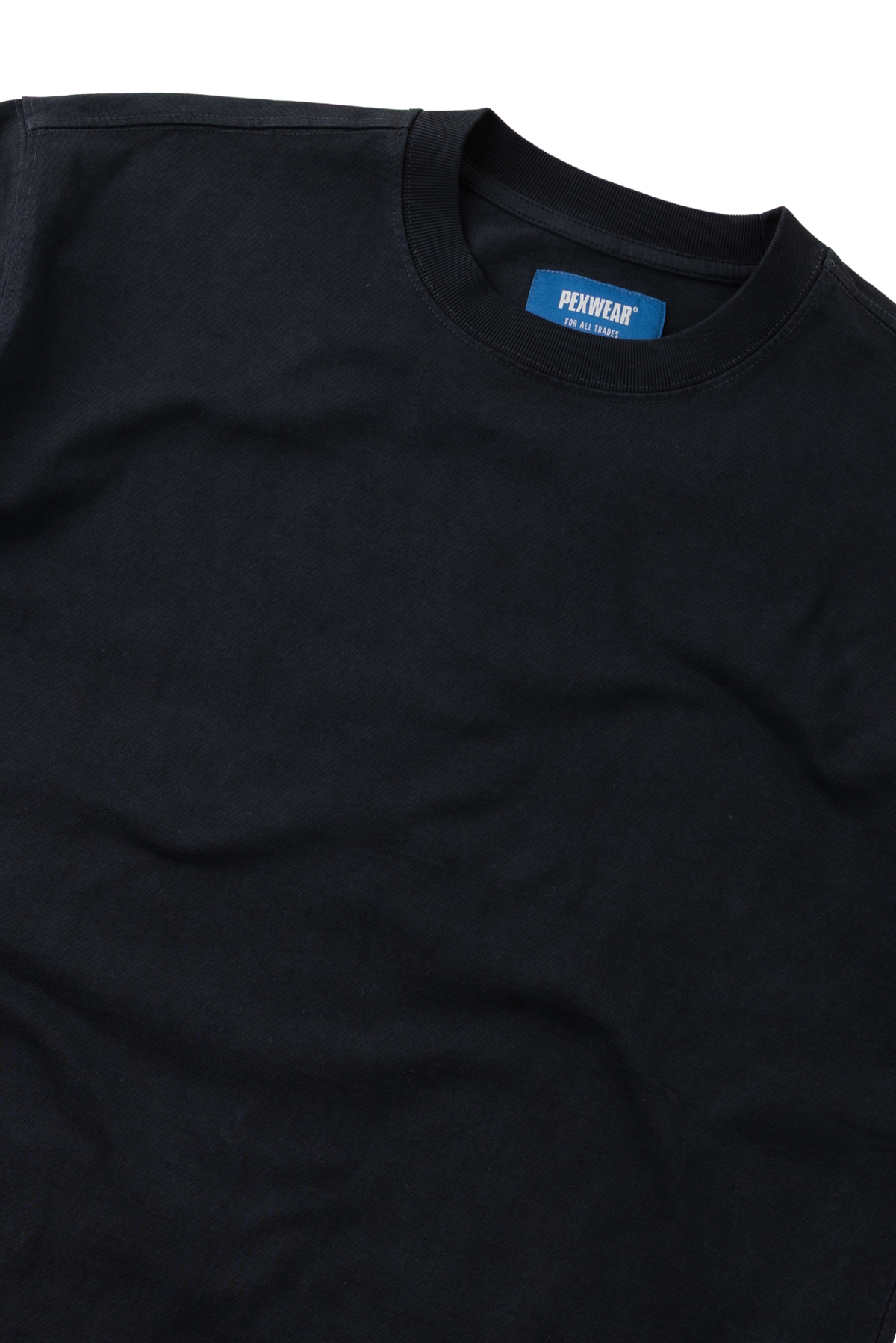 A close-up of a black crewneck t-shirt with a blue neck label that reads 'PETITJEAN'.